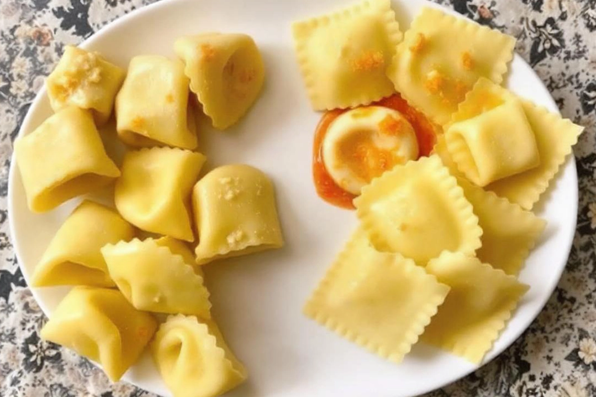 Tortellini and ravioli on a plate, showcasing their shape and size differences.