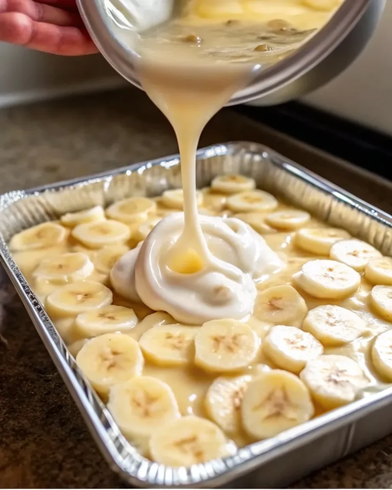 Homemade banana pudding in a glass dish, topped with golden vanilla wafers and fresh banana slices