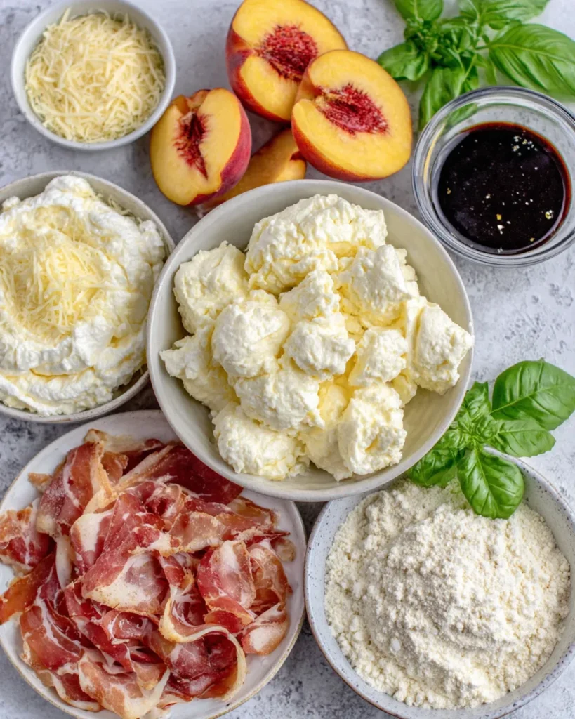 Assorted ingredients for nectarine pizza arranged on a rustic kitchen counter, including fresh nectarines, ricotta, goat cheese, mozzarella, mascarpone, basil, balsamic vinegar, olive oil, and flours.