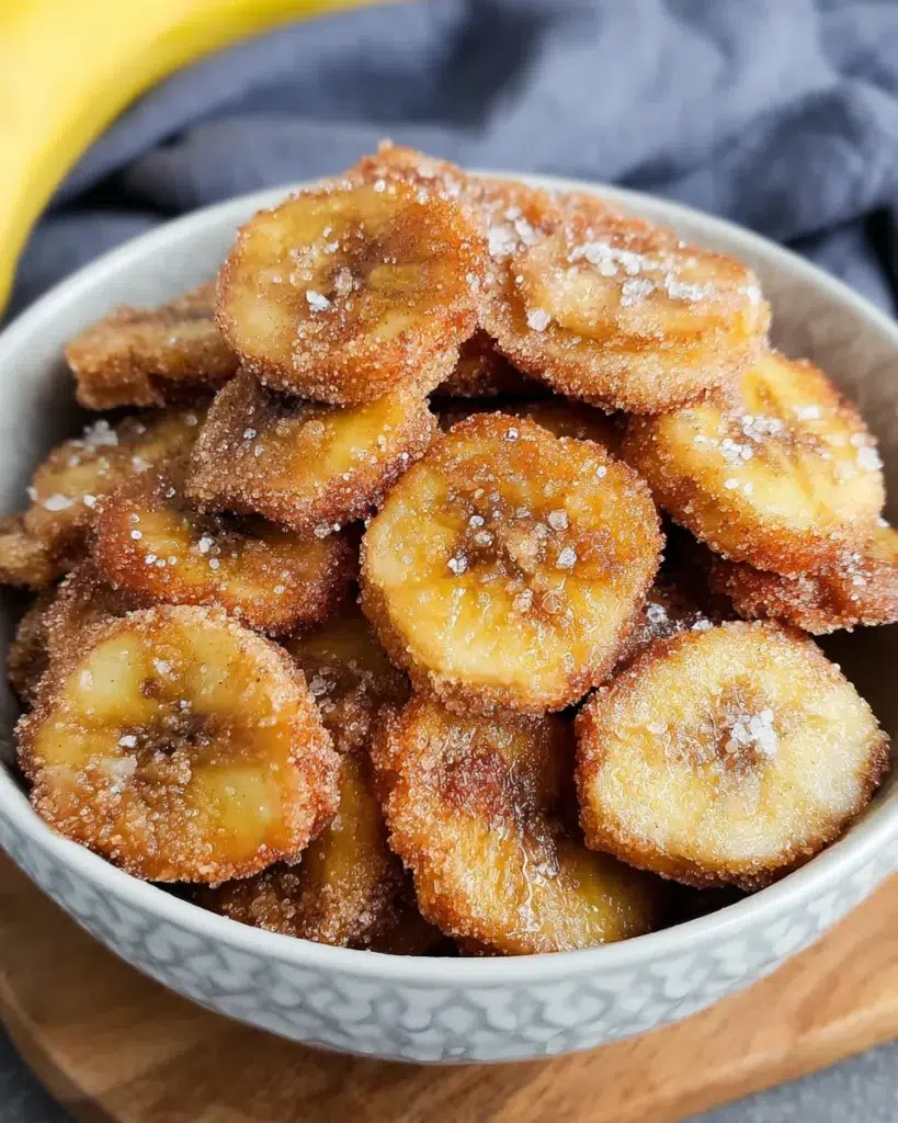 Cinnamon Sugar Air Fryer Banana Chips served on a rustic brunch table with fresh fruit, yogurt bowls, and coffee, crispy and golden with a dusting of cinnamon sugar.