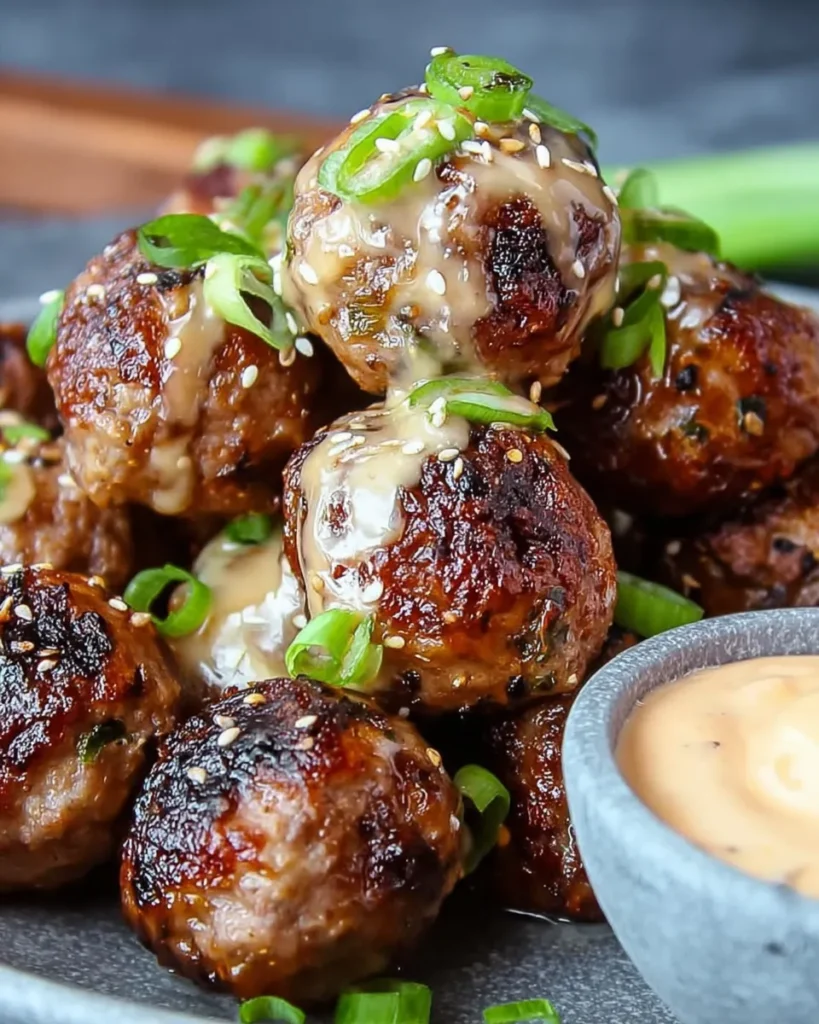 Korean BBQ meatballs served on a rustic wooden table with spicy mayo dip, garnished with sesame seeds and green onions, surrounded by small side dishes for a cozy homemade presentation