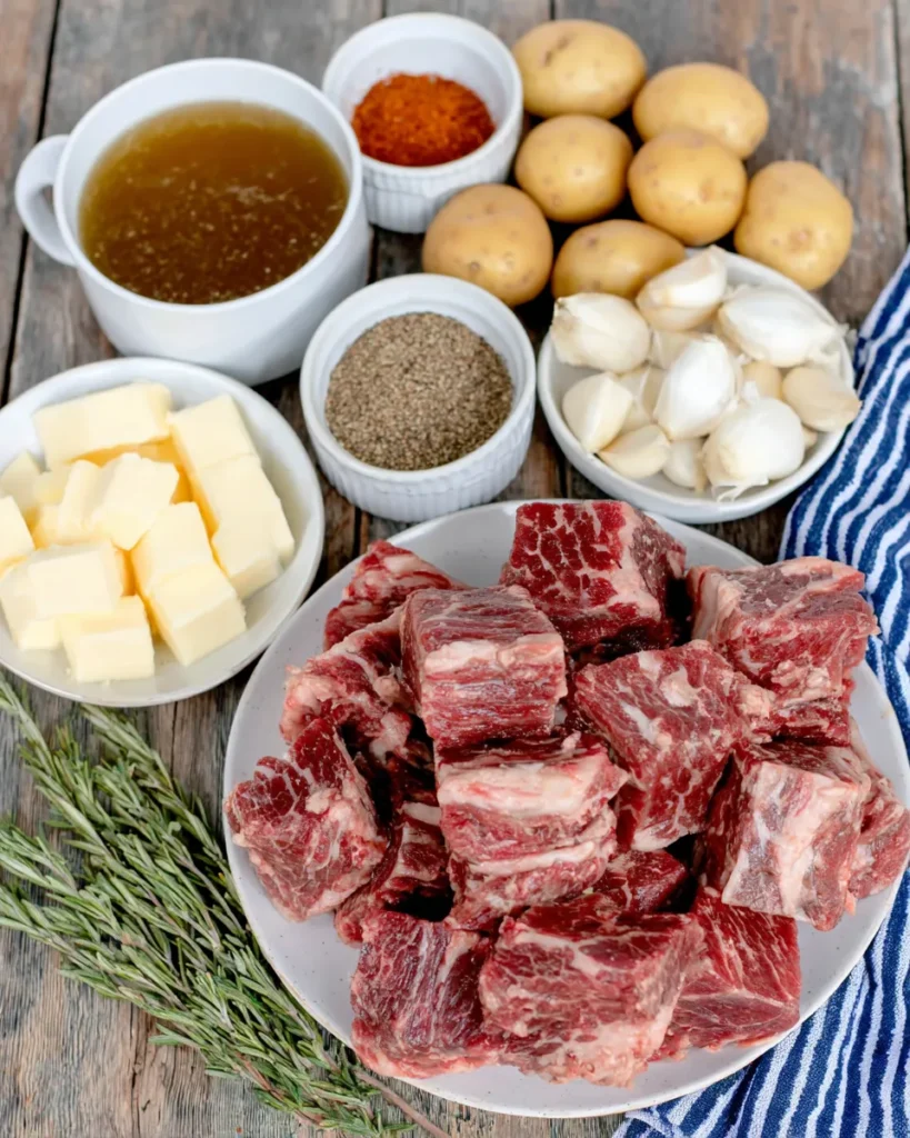 Close-up of garlic butter beef bites with golden baby potatoes in a rich garlic butter sauce, garnished with herbs, served warm in a rustic bowl.