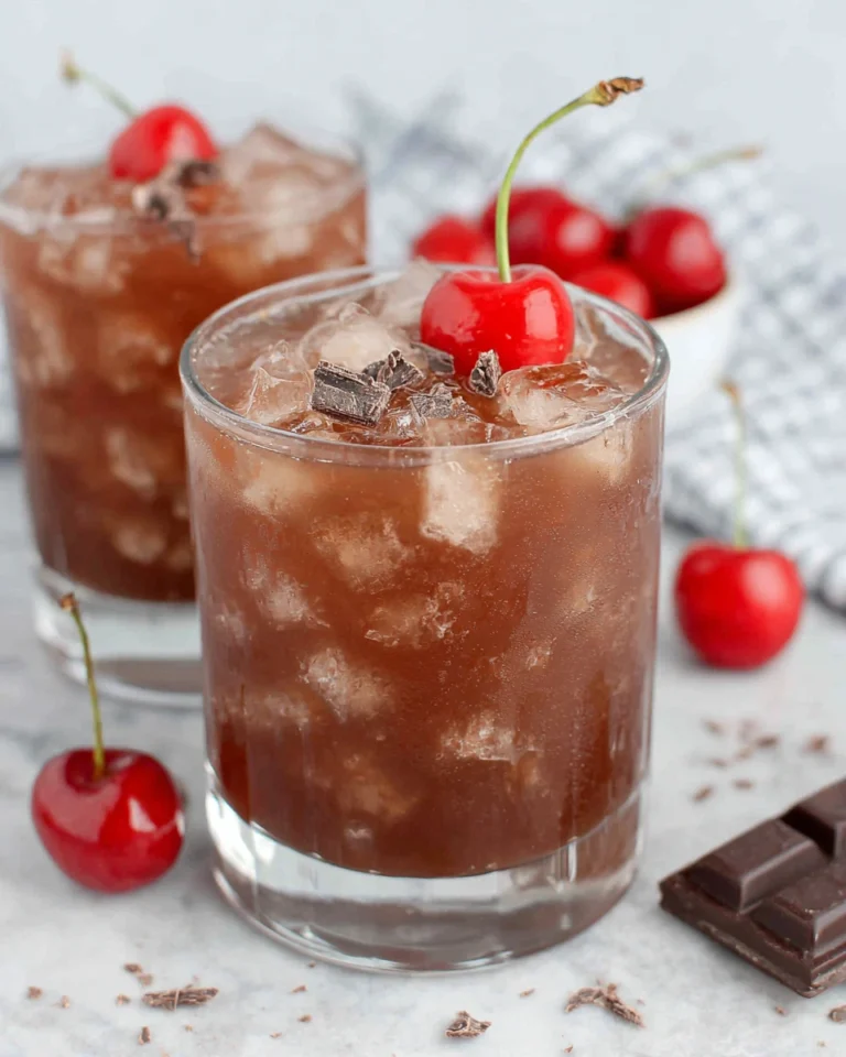 A rich Chocolate Cherry Bourbon Cocktail served over ice in a rocks glass, garnished with a maraschino cherry and shaved chocolate, photographed in natural kitchen light with a cozy homemade feel.
