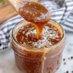 Easy Honey Dijon Vinaigrette Dressing in a small mason jar on a white marble counter, made with olive oil, Dijon mustard, honey, and apple cider vinegar, photographed in natural kitchen lighting with a homemade rustic style.