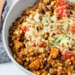 A bowl of One Pot Mexican Lentils made with brown lentils, black beans, sweet potatoes, corn, diced tomatoes, and melted cheddar cheese. This healthy vegetarian one-pot meal is hearty, protein-rich, and perfect for an easy family dinner or meal prep.