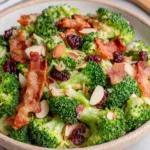 Easy Broccoli Salad served in a white bowl, made with fresh broccoli florets, crispy bacon, sweet dried cranberries, toasted sliced almonds, red onion, and a creamy homemade dressing. A colorful and crunchy Southern-style side dish perfect for potlucks, BBQs, picnics, and family gatherings.