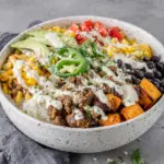 Ground Beef Sweet Potato Taco Bowl with Lime Crema topped with seasoned ground beef, roasted sweet potatoes, black beans, corn, rice, avocado, fresh cilantro, and creamy lime sauce in a homemade Mexican-inspired dinner bowl.