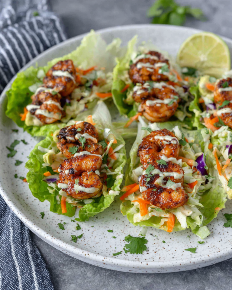 Sheet Pan Chili-Lime Shrimp Lettuce Wraps filled with juicy roasted shrimp, crunchy red cabbage and radish slaw, and creamy avocado sriracha crema served in fresh butter lettuce leaves on a white plate with natural kitchen lighting.