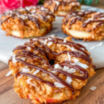 Samoa Apple Slices topped with creamy almond butter coconut filling and chocolate drizzle on a white marble countertop, photographed in natural light with a homemade rustic presentation.