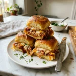 Close-up of homemade Hot Honey Chipotle Chicken Sliders stacked on a wooden board with soft golden Hawaiian rolls, juicy chipotle chicken, creamy honey chipotle mayo, melted mozzarella and cheddar cheese, brushed with hot honey butter and garnished with fresh parsley.