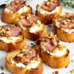 Million Dollar Bacon Goat Cheese Crostini served on a platter with crispy candied bacon pressed into creamy goat cheese, surrounded by golden toasted baguette slices and drizzled with hot honey, an easy homemade party appetizer.