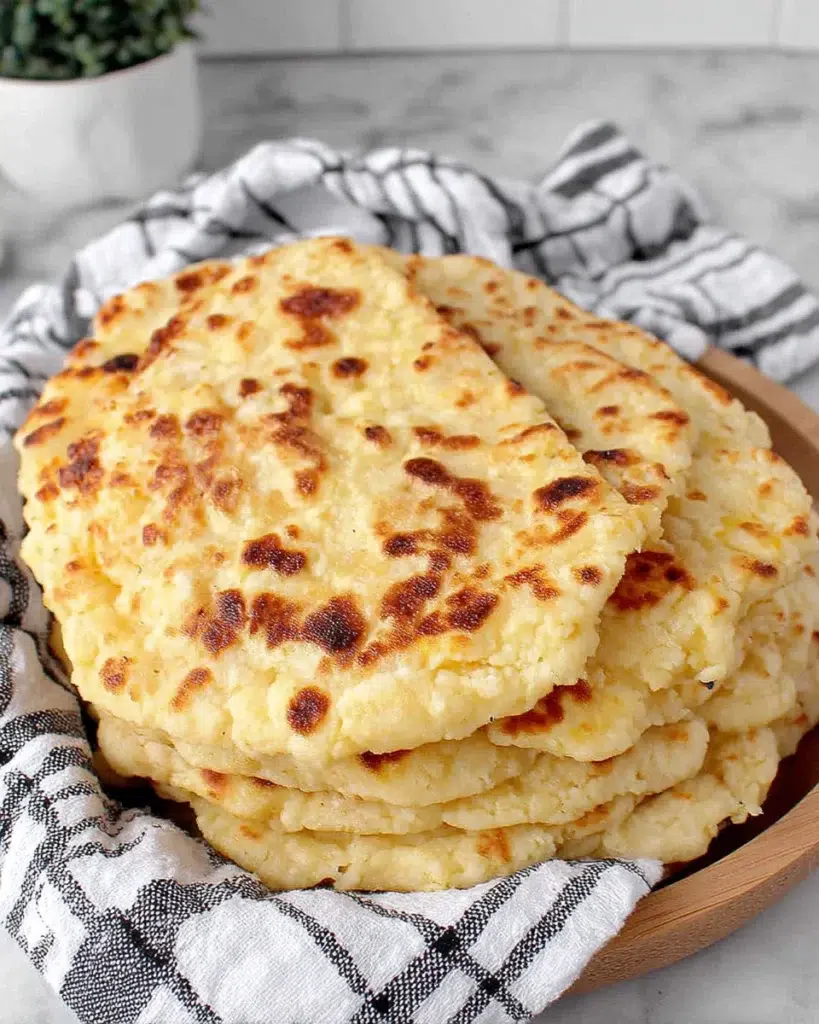 Soft homemade cottage cheese tortillas made with cottage cheese, flour, baking powder, and salt, stacked on a white marble counter in a home kitchen.