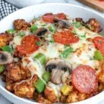 Low Carb Crustless Pizza Bowl with Italian sausage, mushrooms, green bell pepper, onion, marinara sauce, melted Italian cheese, and pepperoni served in a bowl on a white marble kitchen counter.