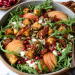 Autumn Harvest Honeycrisp Apple and Feta Salad with crisp apple slices, crumbled feta, pomegranate arils, avocado, arugula, crispy prosciutto, and maple-spiced pecans on a white marble counter.